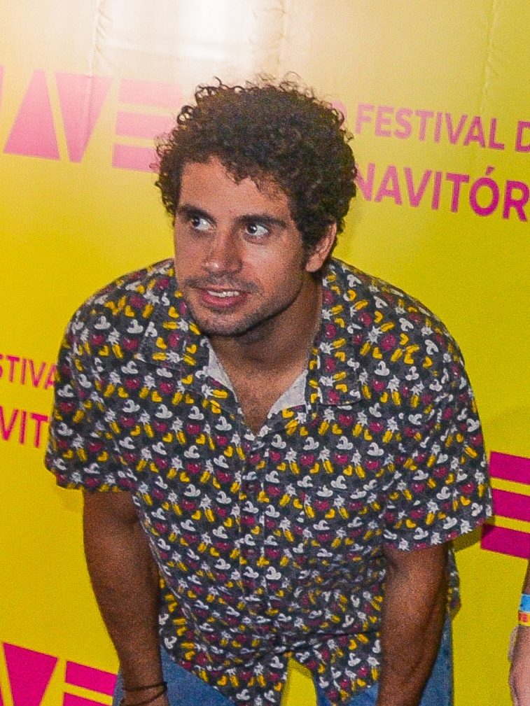 Chicão rindo, de boné e jaqueta preta